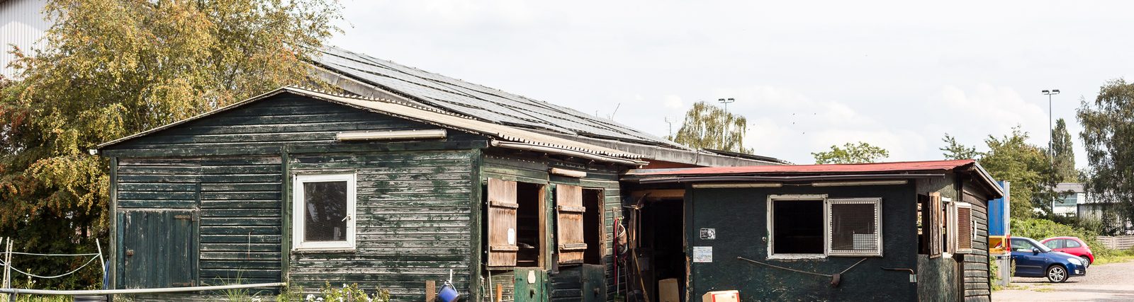 Der alte Ponystall aus dunkelgrünem Holz mit weißen Fenstern
